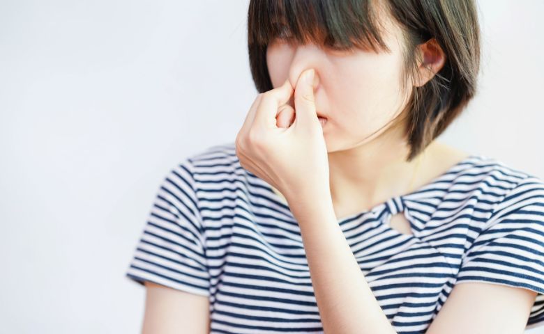 鼻をつまむ女性